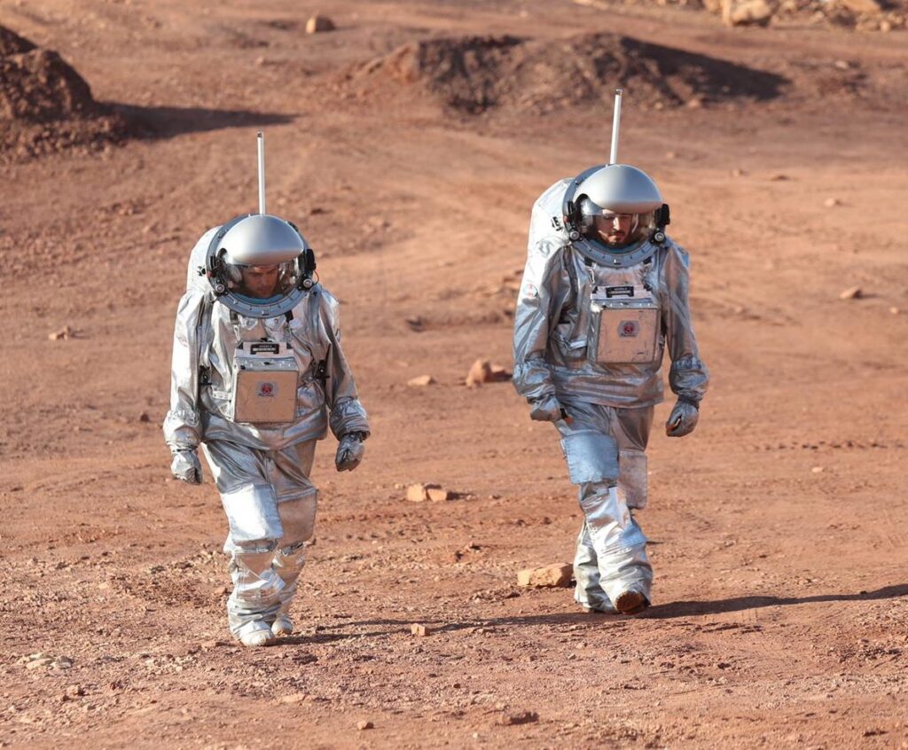 Two analog astronauts walking on Mars-like terrain